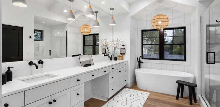 A bathroom remodeled into a luxurious design with glass enclosed shower area, a freestanding bathtub, and a wide vanity area