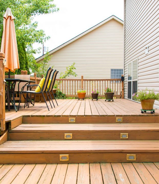 Hardwood deck for patio with plant ornaments, table and chairs, and an umbrella.