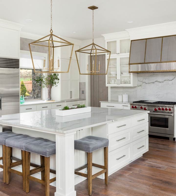 A spacious kitchen with an island, cushioned stools, appliances, and white cabinets